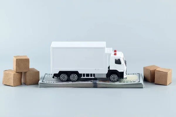 White toy truck with boxes on a light background, space for text. Logistics and wholesale trade concept.