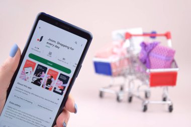 Kharkiv, Ukrayna, 31 Mart 2023: Akıllı telefonlu alışveriş arabası pembe arka planda Joom logosunu açtı.