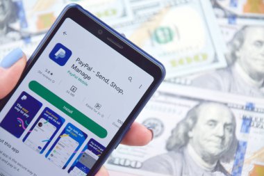 Kharkiv, Ukrayna - 13 Mart 2023: PayPal mobil bankacılık uygulaması akıllı telefon ekranında. Amerikan dolar banknotlarının arka planı.