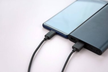 Mobil cihazları şarj etmek için güç bankası. Güç bankası olan siyah akıllı telefon şarj aleti. Mobil aygıtlar için dış pil.