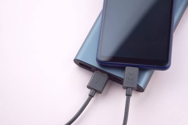 Mobil cihazları şarj etmek için güç bankası. Güç bankası olan siyah akıllı telefon şarj aleti. Mobil aygıtlar için dış pil.