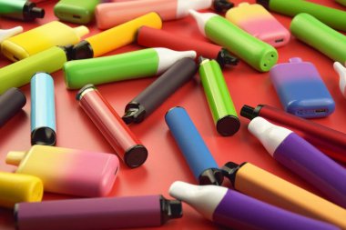 Kırmızı arka planda tek kullanımlık elektronik sigara seti. Modern sigara, buhar ve nikotin konsepti.