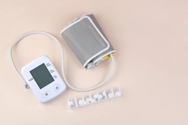 Dijital kan basıncı tonometresi ve arka planda fotokopi alanı olan bir kutu hap. Sağlık hizmetleri ve tıbbi kavramlar.