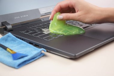 Kharkiv, Ukrayna, 11 Temmuz 2023: Laptop klavyesindeki tozları temizlemek için yeşil yumuşak temizlik jeli Asus Rog Strix. Bilgisayar klavyeni temizleme konsepti. Ofis temizliği.