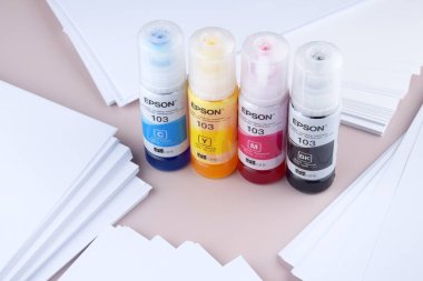 KHARKIV, UKRAINE - FEBRUARY 11, 2023: Four bottles of ink Epson, yellow, red, blue, black, built-in to the Epson L3150 series printer. clipart