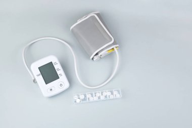 Dijital kan basıncı tonometresi ve mavi arka planda fotokopi alanı olan bir kutu hap. Sağlık hizmetleri ve tıbbi kavramlar.