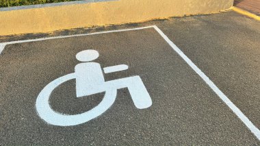 Otoparktaki asfalt yolda engelli işareti var. Trafik işareti..