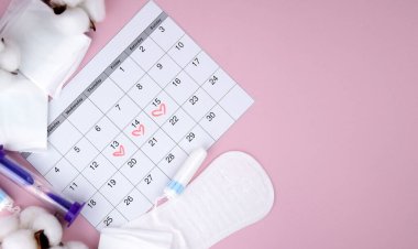 Kadınların adet pedleri, tamponlar, adet takvimi ve pembe arka planda çalar saat. Kritik günler dönemi. Metin için yer.
