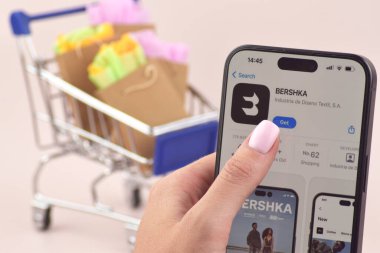 KHARKOV, UKRAINE - 18 Ağustos 2024: Akıllı telefonlu alışveriş arabası ekranda Bershka uygulaması açık.