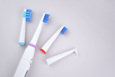 Modern electric ultrasonic toothbrush with rechargeable battery on a gray surface. Teeth care. clipart