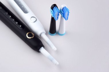 Gri yüzeyinde şarj edilebilir bataryası olan modern elektrikli ultrasonik diş fırçası. Diş bakımı.
