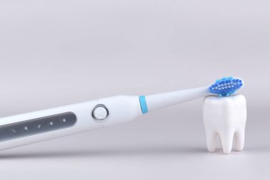 Gri yüzeyinde şarj edilebilir bataryası olan modern elektrikli ultrasonik diş fırçası. Diş bakımı.