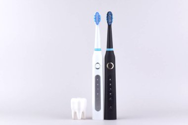 Gri yüzeyinde şarj edilebilir bataryası olan modern elektrikli ultrasonik diş fırçası. Diş bakımı.