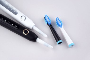 Gri yüzeyinde şarj edilebilir bataryası olan modern elektrikli ultrasonik diş fırçası. Diş bakımı.