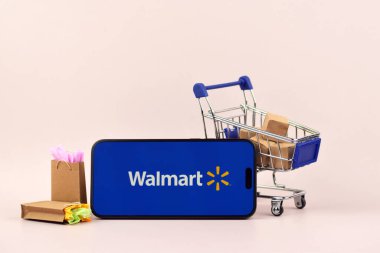 KHARKOV, UKRAINE - 18 Ağustos 2024: Akıllı telefonlu alışveriş arabası mavi arka planda Walmart açık.