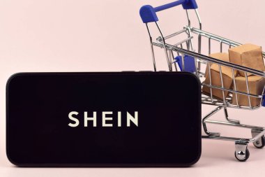 KHARKOV, UKRAINE - 18 Ağustos 2024: Akıllı telefonlu alışveriş arabası siyah arka planda Shein açık.