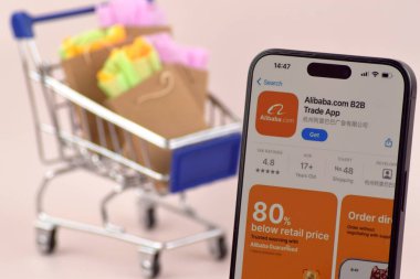 KHARKOV, UKRAINE - 18 Ağustos 2024: Akıllı telefonlu alışveriş arabası ekranda Alibaba uygulaması açık.
