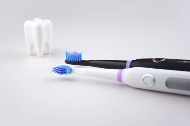 Gri yüzeyinde şarj edilebilir bataryası olan modern elektrikli ultrasonik diş fırçası. Diş bakımı.