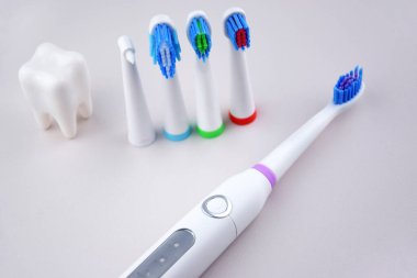 Gri yüzeyinde şarj edilebilir bataryası olan modern elektrikli ultrasonik diş fırçası. Diş bakımı.