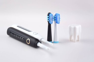 Gri yüzeyinde şarj edilebilir bataryası olan modern elektrikli ultrasonik diş fırçası. Diş bakımı.