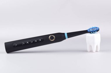 Gri yüzeyinde şarj edilebilir bataryası olan modern elektrikli ultrasonik diş fırçası. Diş bakımı.