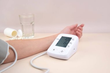 Dijital kan basıncı tonometresi ve arka planda fotokopi alanı olan bir kutu hap. Sağlık hizmetleri ve tıbbi kavramlar.