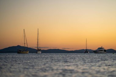 Avustralya 'da dalgalar ve yatlarla altın ışık altında gün batımı