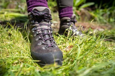 İlkbaharda yürüyüş yapan bir kız tarafından yürüyüş botlarına ayakkabı bağcıkları bağlanmış.