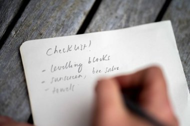 gril writing a camping list in a piece of paper. writing a check list with a pencil in australia