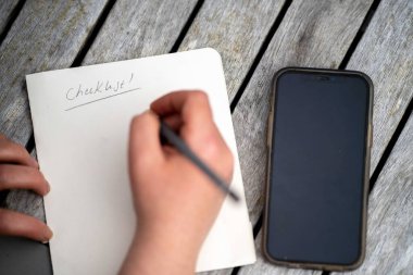 gril writing a camping list in a piece of paper. writing a check list with a pencil in australia