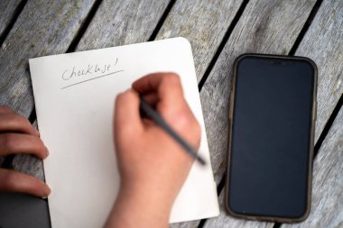 gril writing a camping list in a piece of paper. writing a check list with a pencil in australia