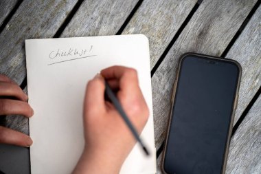 gril writing a camping list in a piece of paper. writing a check list with a pencil in australia