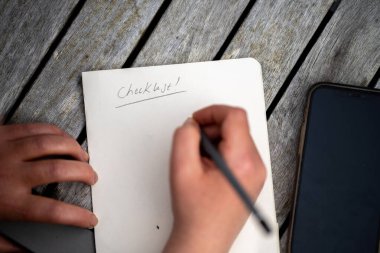 gril writing a camping list in a piece of paper. writing a check list with a pencil in australia