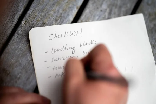 gril writing a camping list in a piece of paper. writing a check list with a pencil in australia