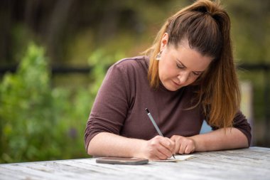 mature university student writing outside studying in australia