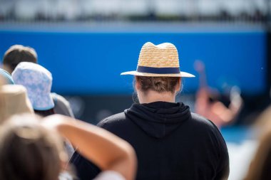 tennis fan watching a tennis match at the australian open eating food and drinking