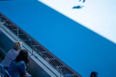 tennis fan watching a tennis match at the australian open eating food and drinking
