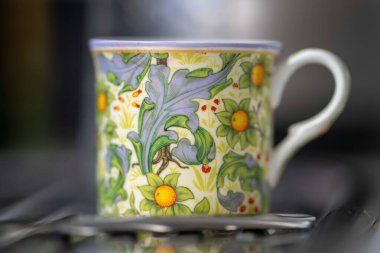 Tahta bir masada çiçekli bir fincan çay.