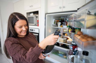 Getting food out of the fridge. Beer in the fridge. Fridge full of food. Freezer full of food. Person deciding what they what for dinner from the fridge in australi