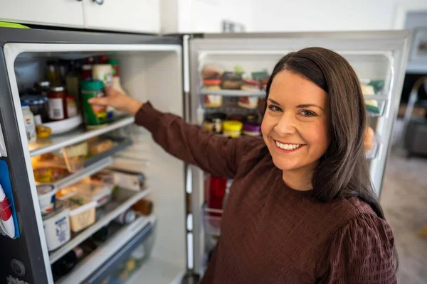 Getting food out of the fridge. Beer in the fridge. Fridge full of food. Freezer full of food. Person deciding what they what for dinner from the fridge in australi