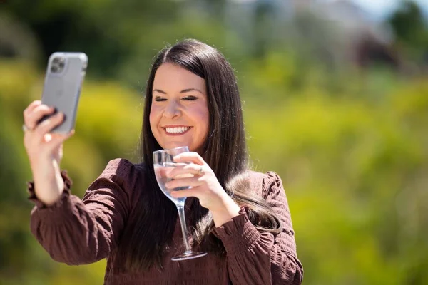 Girl video calling her friends on a zoom call. Woman on holiday skyping her family outside in a beautiful place in australia