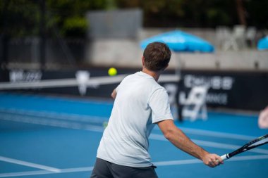 Amateur playing tennis at a tournament and match on grass in Melbourne, Australia in summer