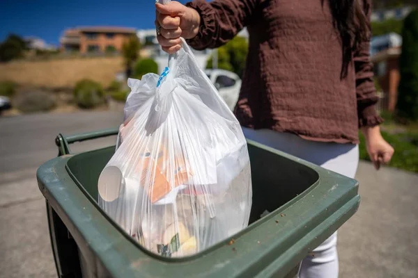 Throwing rubbish in the bin and sorting recycling. Putting rubbish in an inside bin in australia