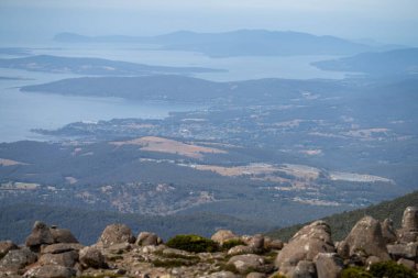 peak of a rocky mountain in a national park looking over a city below, mt wellington hobart tasmania australia in summer