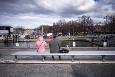 Avustralya 'da su kenarında bir bankta oturuyor.