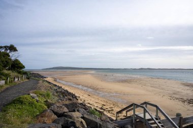 Phillip Adası 'nda alacakaranlıkta yüzen aileleri olan kumlu bir sahil. 