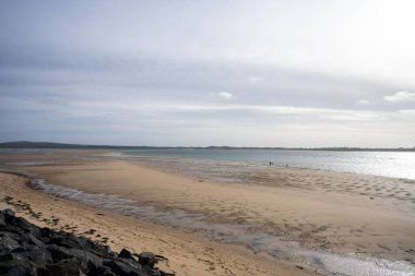 Phillip Adası 'nda alacakaranlıkta yüzen aileleri olan kumlu bir sahil. 