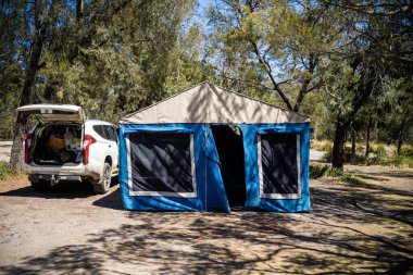 İzole edilmiş bir kamp alanında kamp yapan mavi çadırlı çadırlar ve karavanlar.