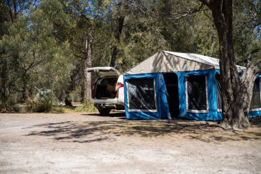 İzole edilmiş bir kamp alanında kamp yapan mavi çadırlı çadırlar ve karavanlar.