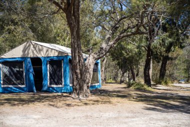İzole edilmiş bir kamp alanında kamp yapan mavi çadırlı çadırlar ve karavanlar.
